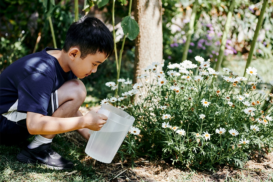 Young boy watering flowers for real world STEM education