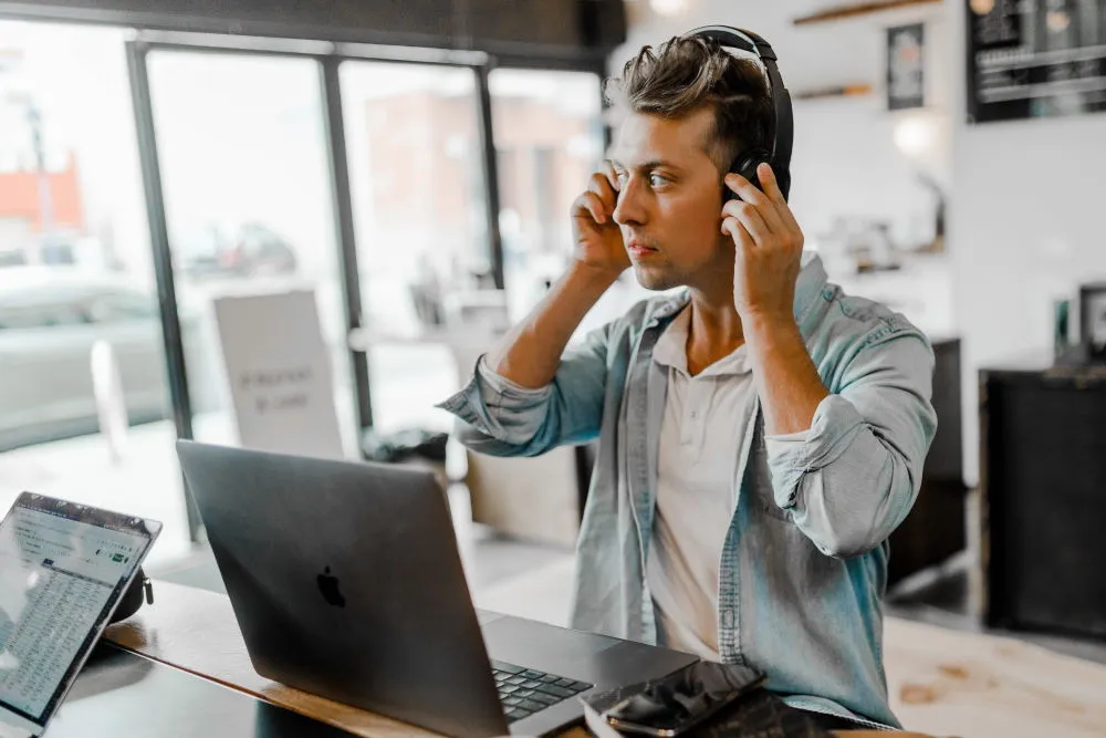 A man wearing a headset listening to the Derek Prince Legacy Radio podcast on his laptop