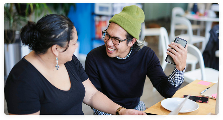 Two people talking and laughing while working.
