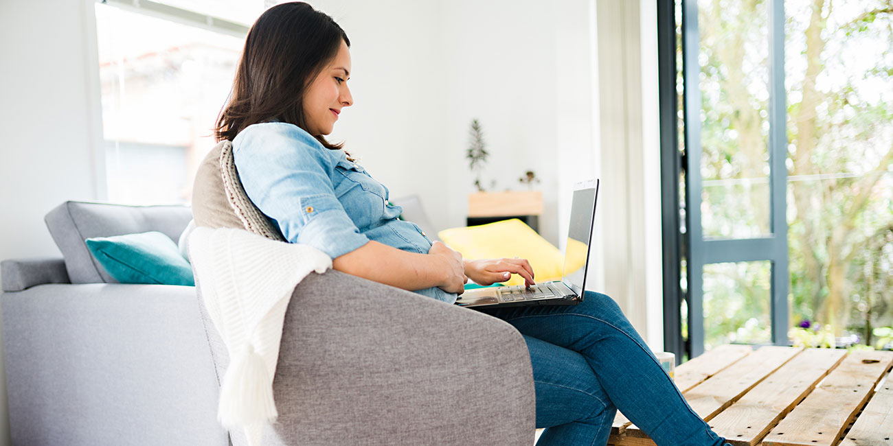 Pregnant woman on maternity leave working from home on laptop