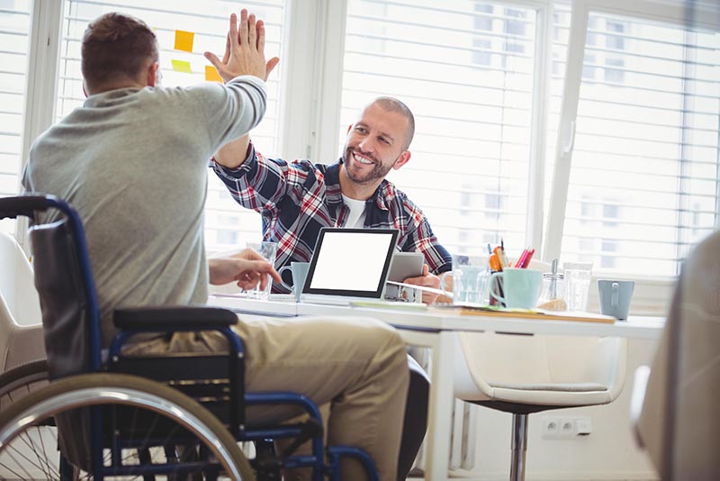 Two men high-fiving at a desk