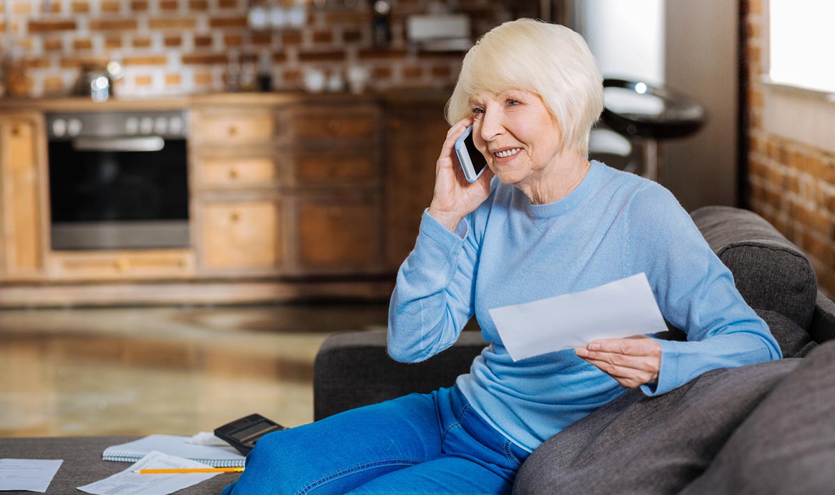 A woman talks on a phone while holding a piece of paper