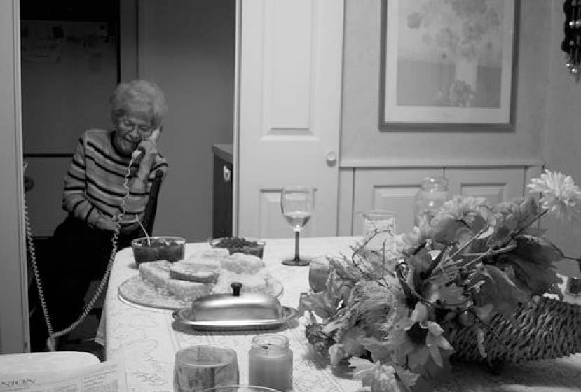 A woman on a corded phone in front of a holiday table