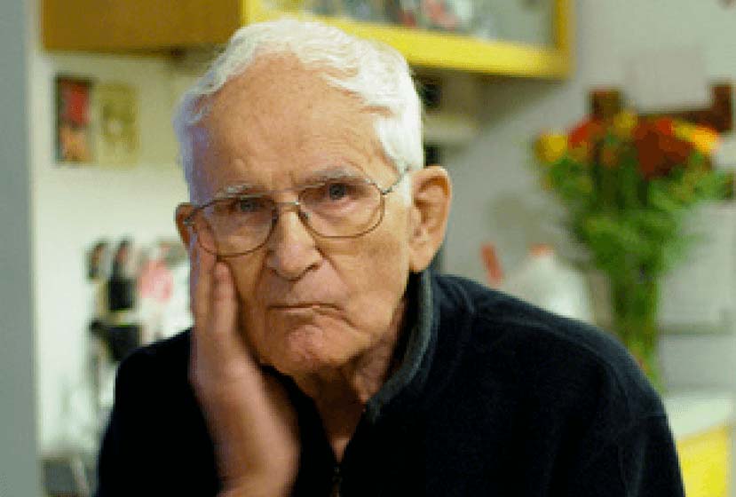 A man with his hand on his face looks at the camera
