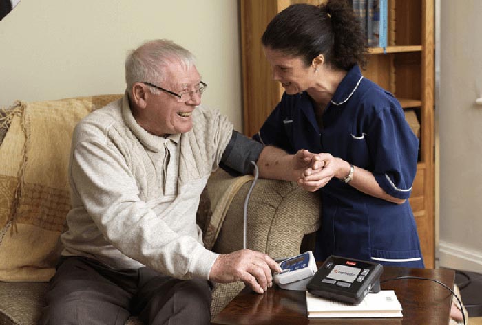 A caregiver checks a man's blood pressure