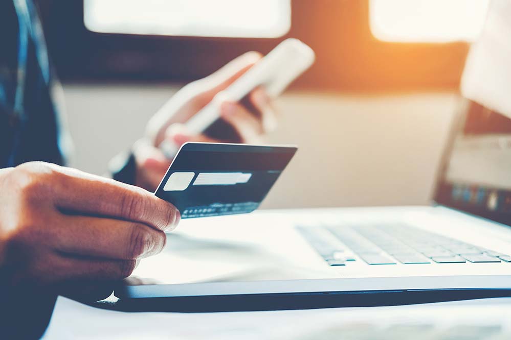 Someone reviews a credit card while at a computer