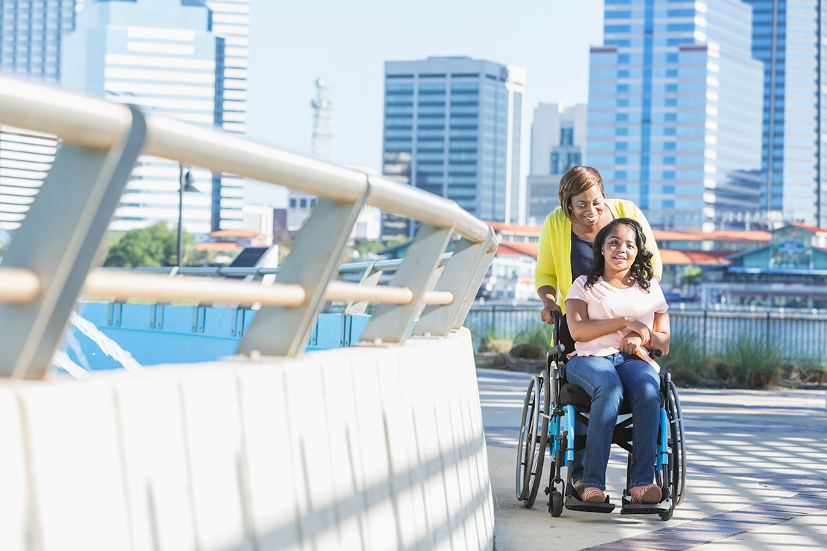 A mother pushes her daughter in a wheelchair