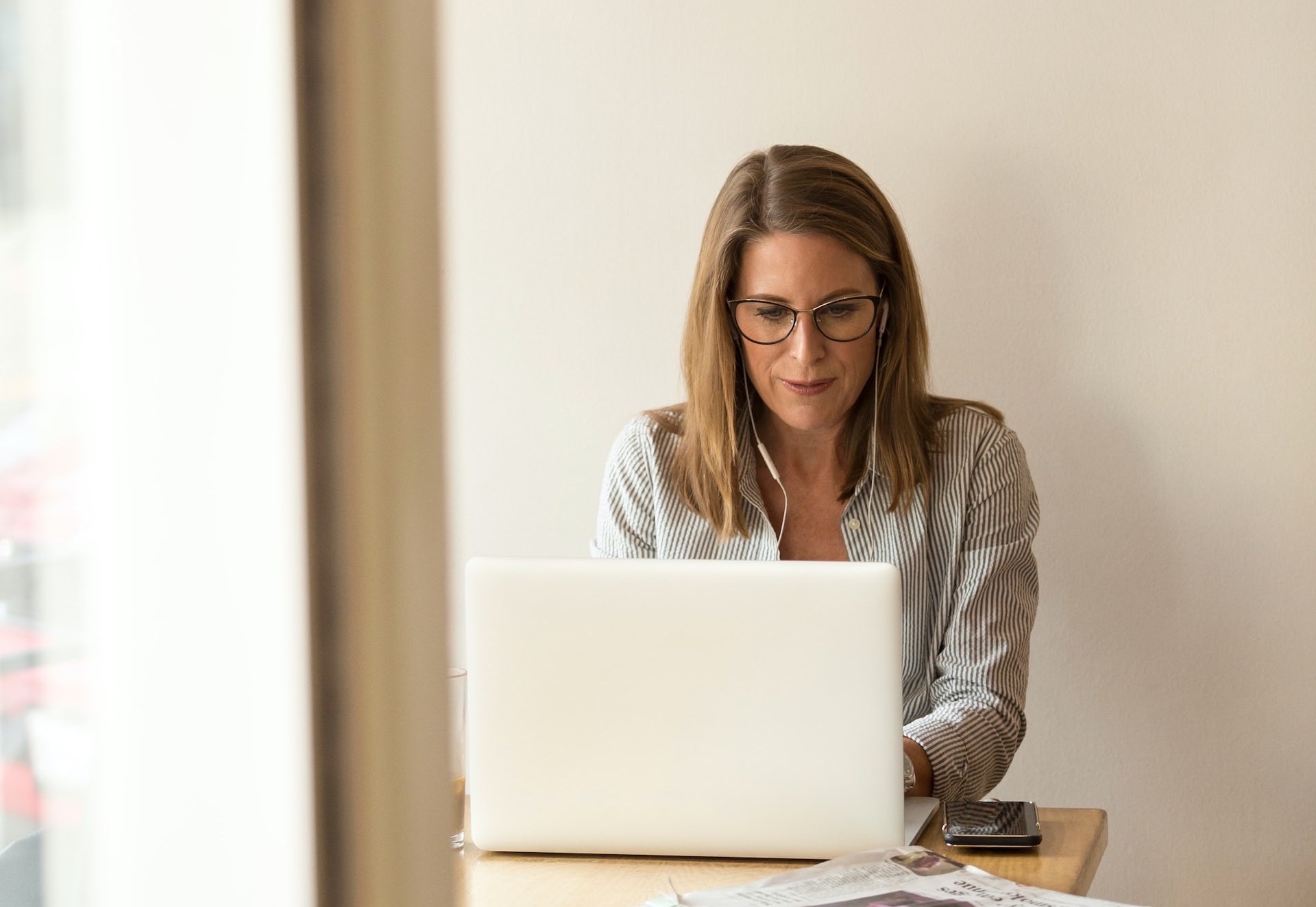 a woman sitting at a table on her laptop 