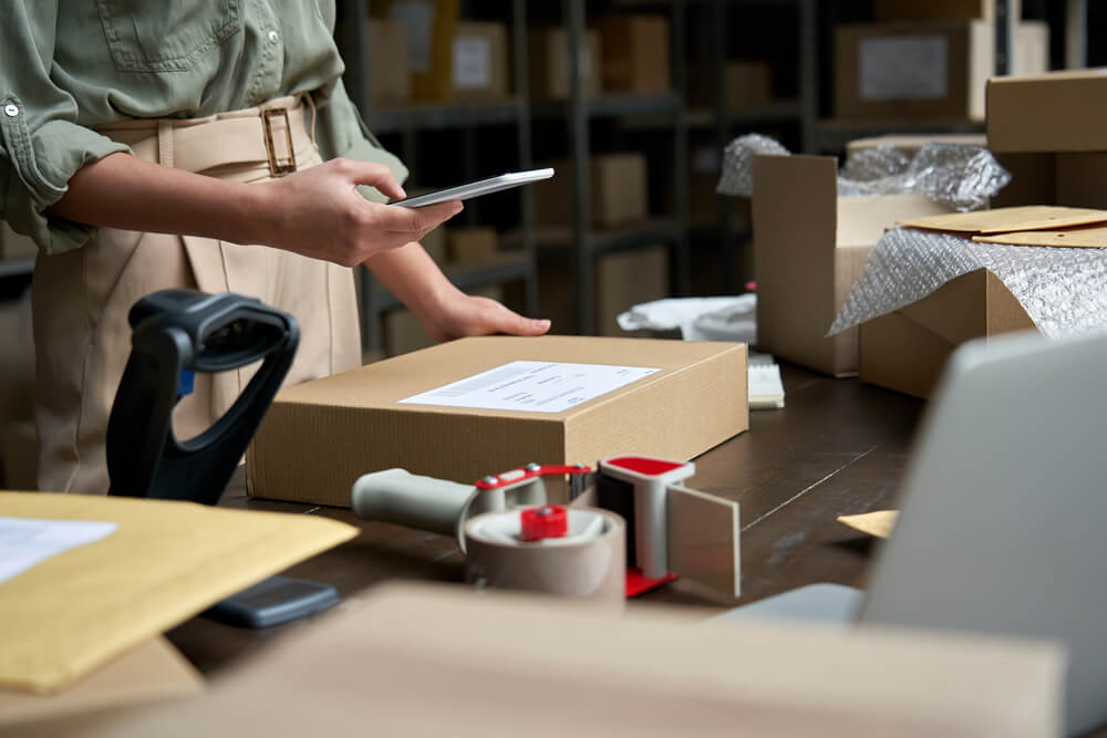 A woman holding a tablet while managing her packages inventory