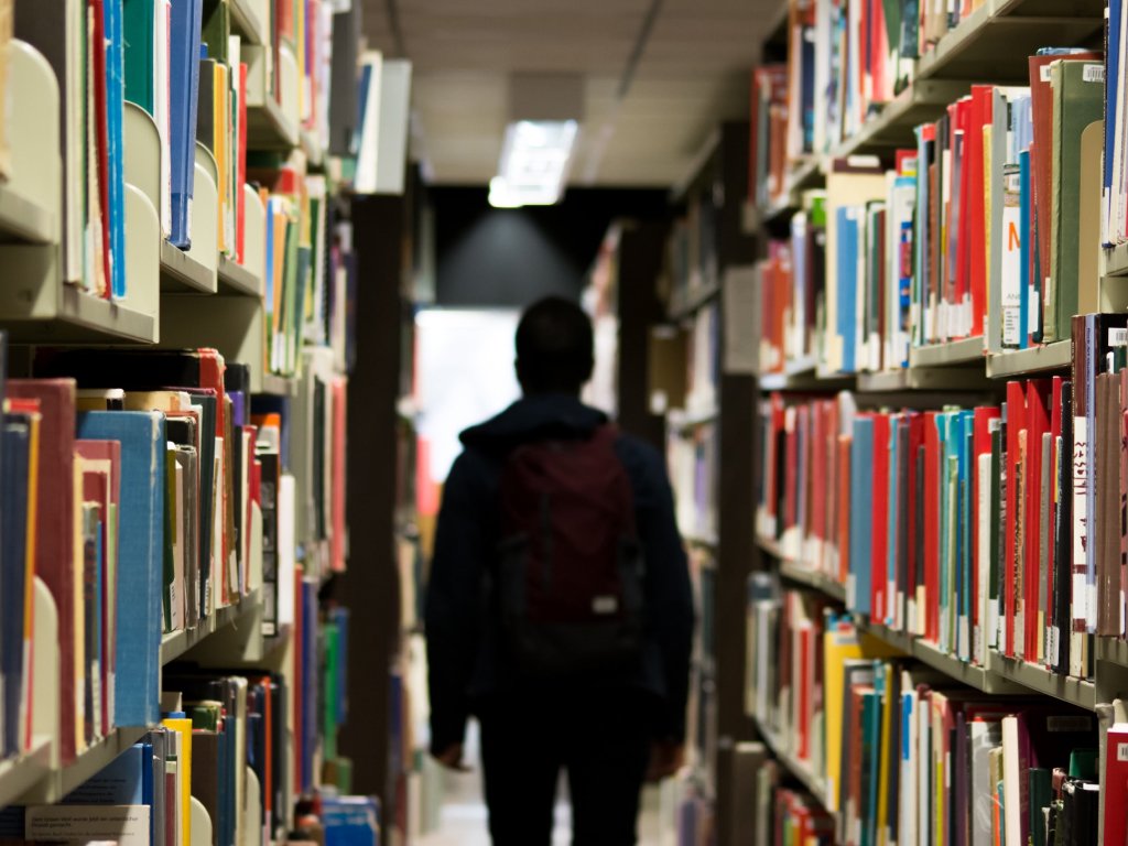 aluno buscando livro ideal em biblioteca