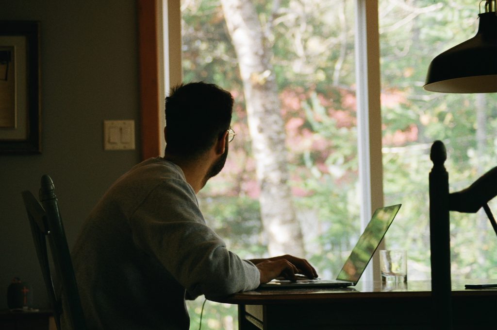 Men looking to an open window while he workes remotely