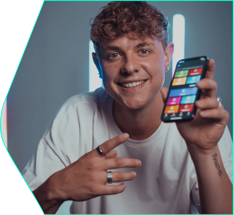 Image of a smiling guy holding a mobile phone in his hand and pointing at it - Simple Club