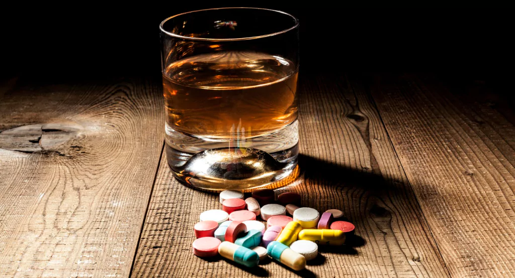 Probiotic supplements kept on a table near a glass of alcohol