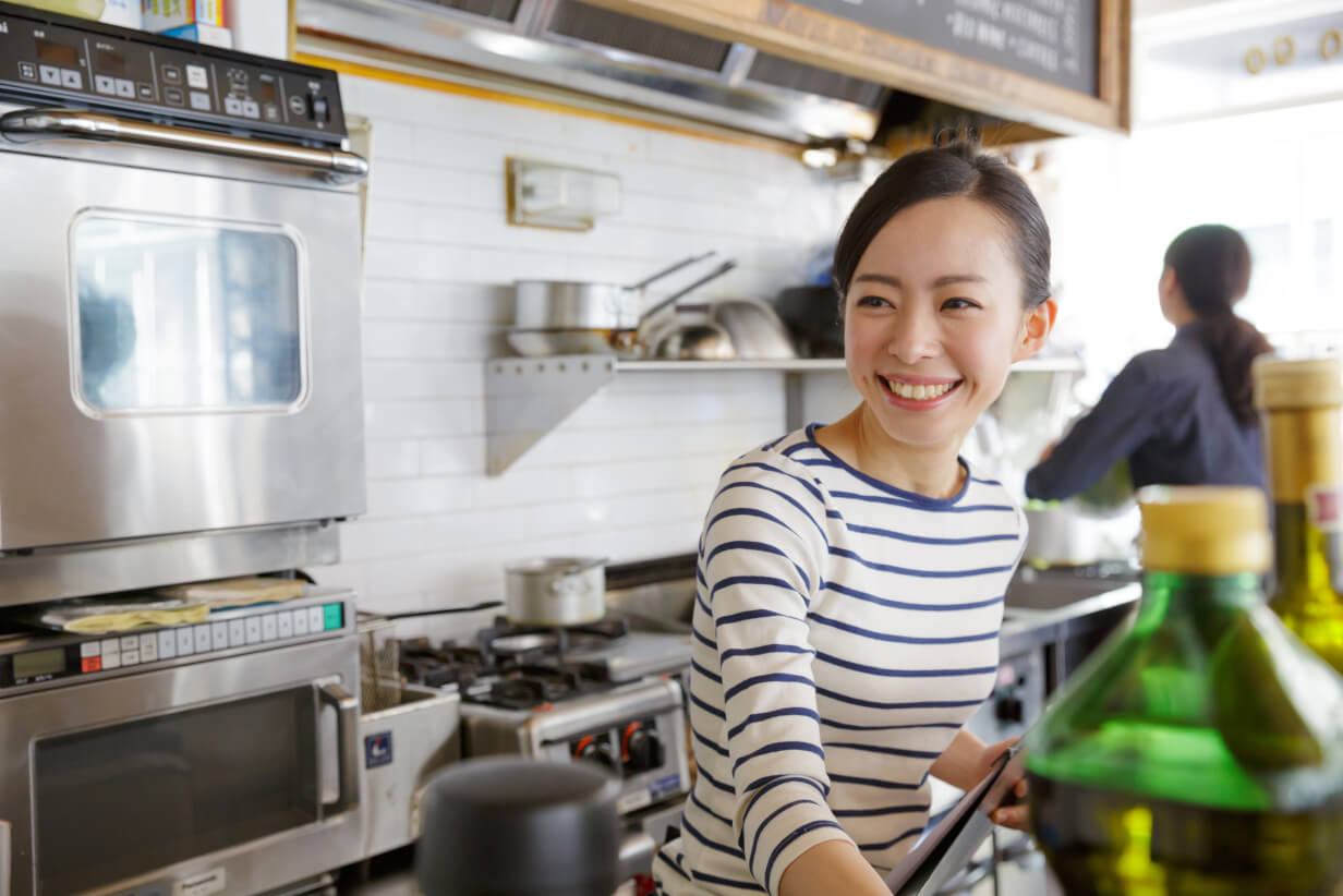 Female manger working at her restaurant's kitchen and smiling to her Thriver Partner Manager