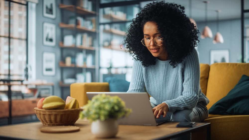Donor database: Woman sitting on a couch while using her laptop