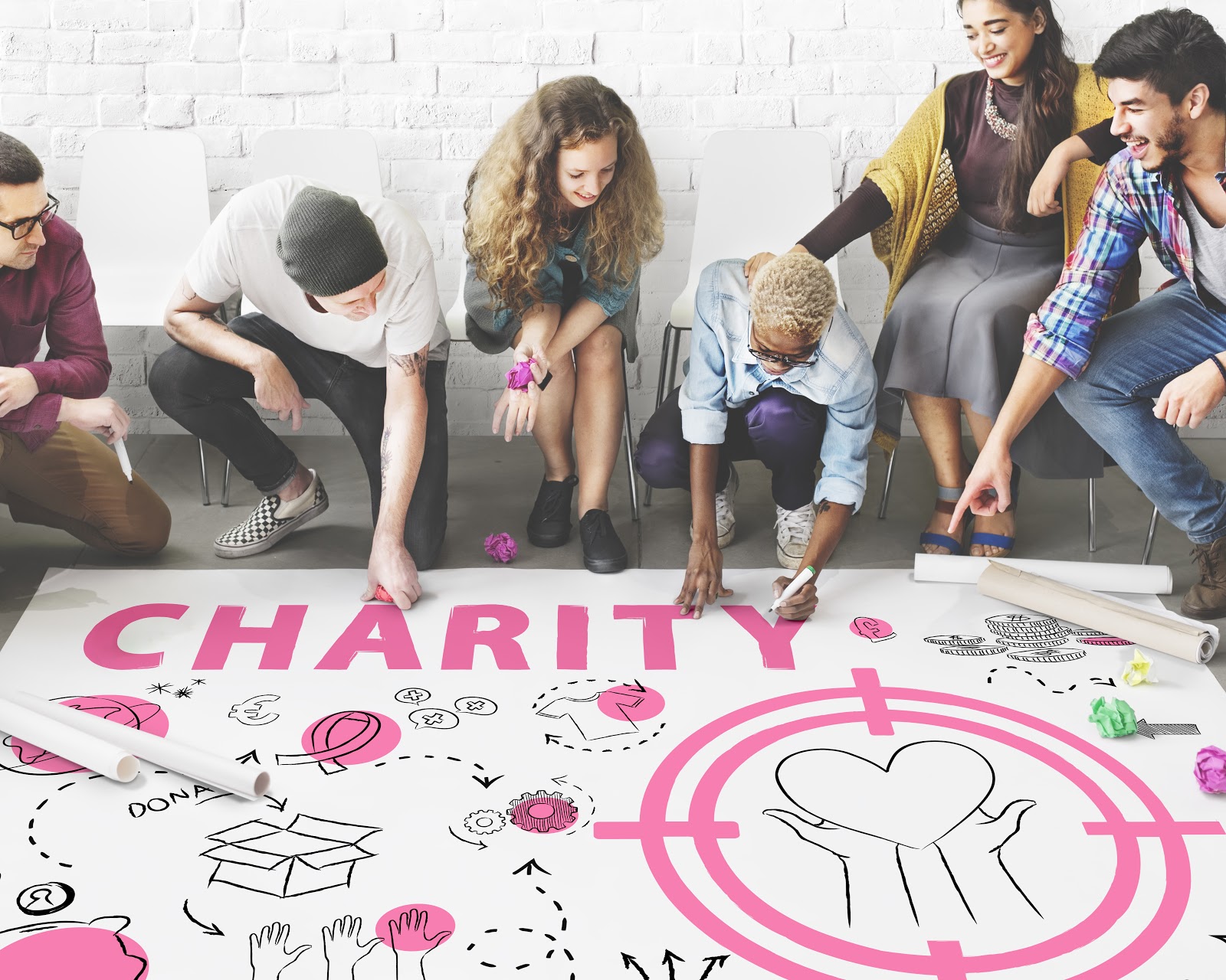Virtual fundraising events: Group of people drawing on large poster that reads "Charity"
