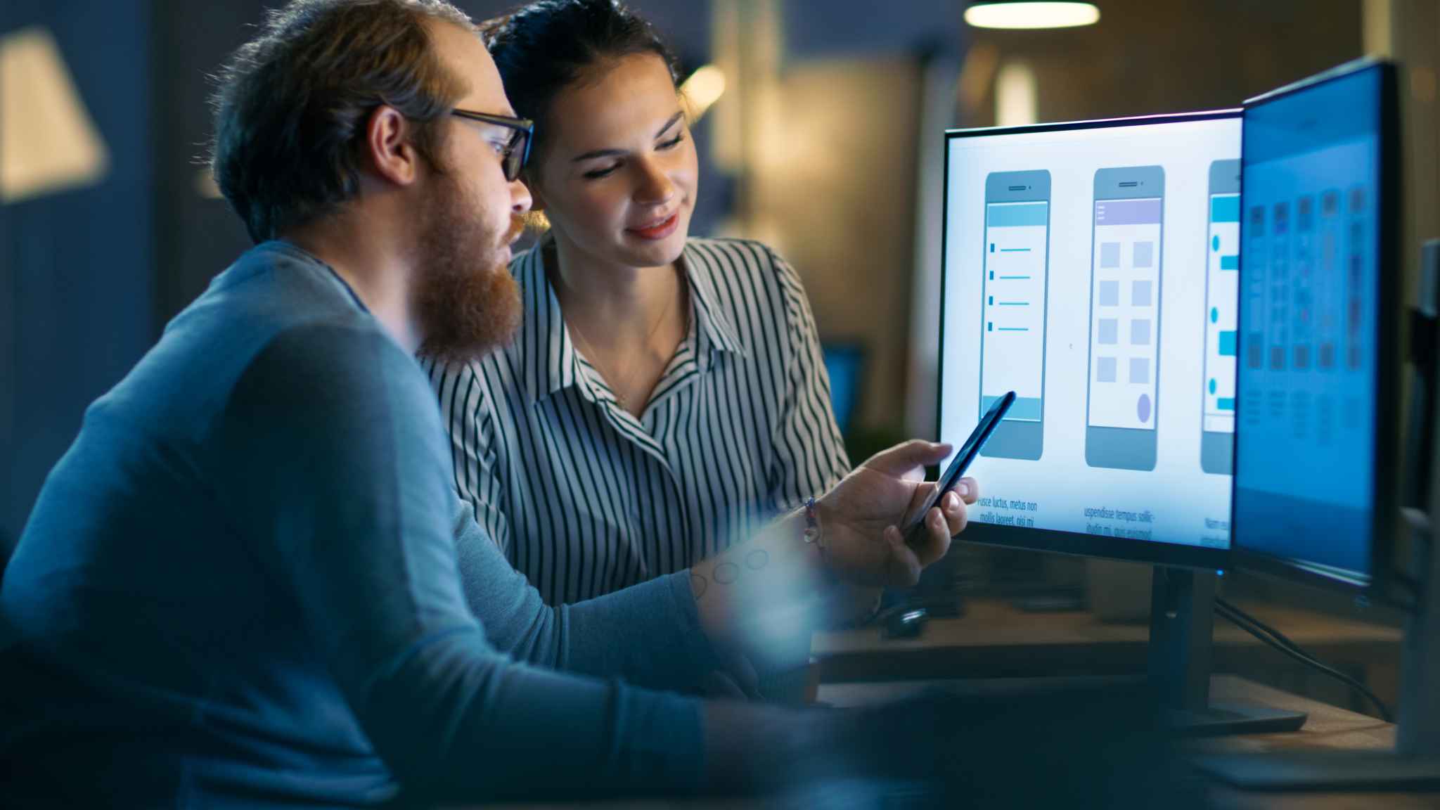 Man and woman looking at a computer screen for mobile app design and engineering