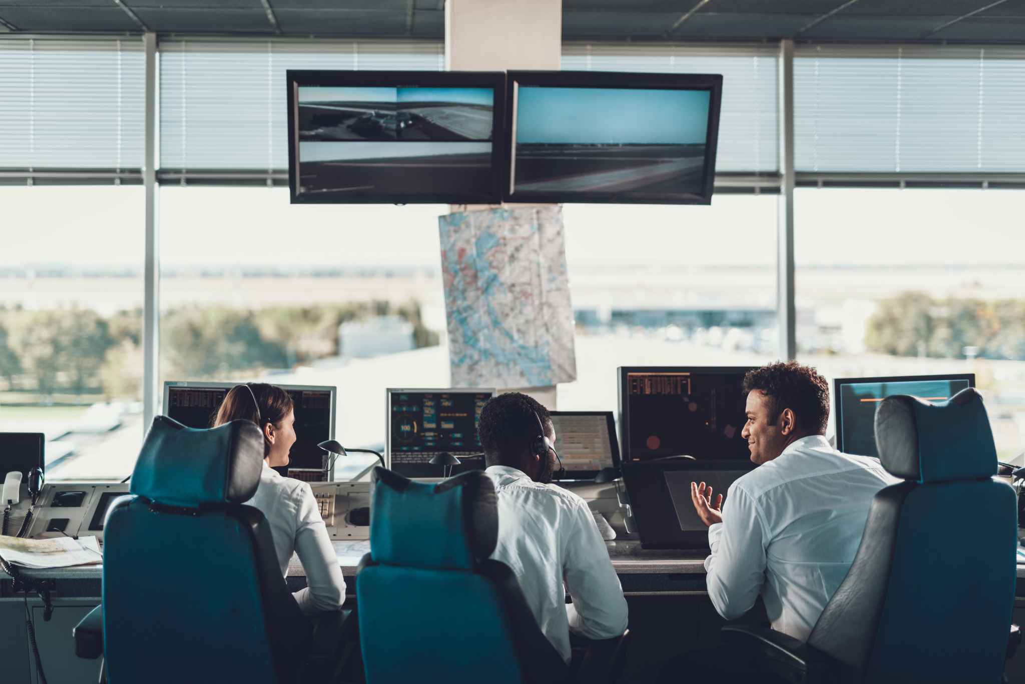Traffic management center with three individuals speaking in front of a window