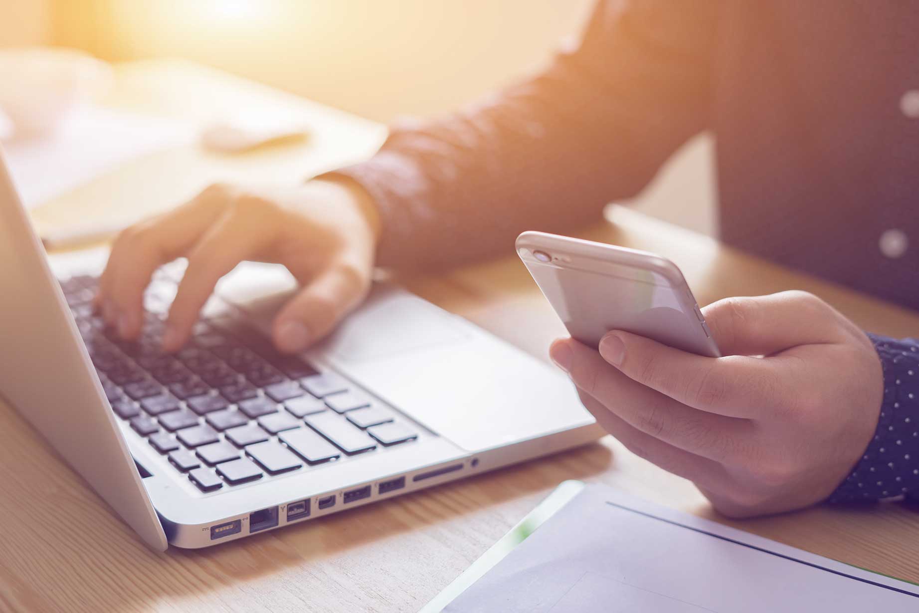 Man on both laptop and cell phone entering information