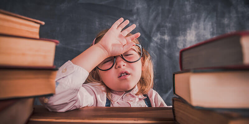 Do I need a solicitor when buying a house at auction: Image of a frustrated tired kid with a pile of books