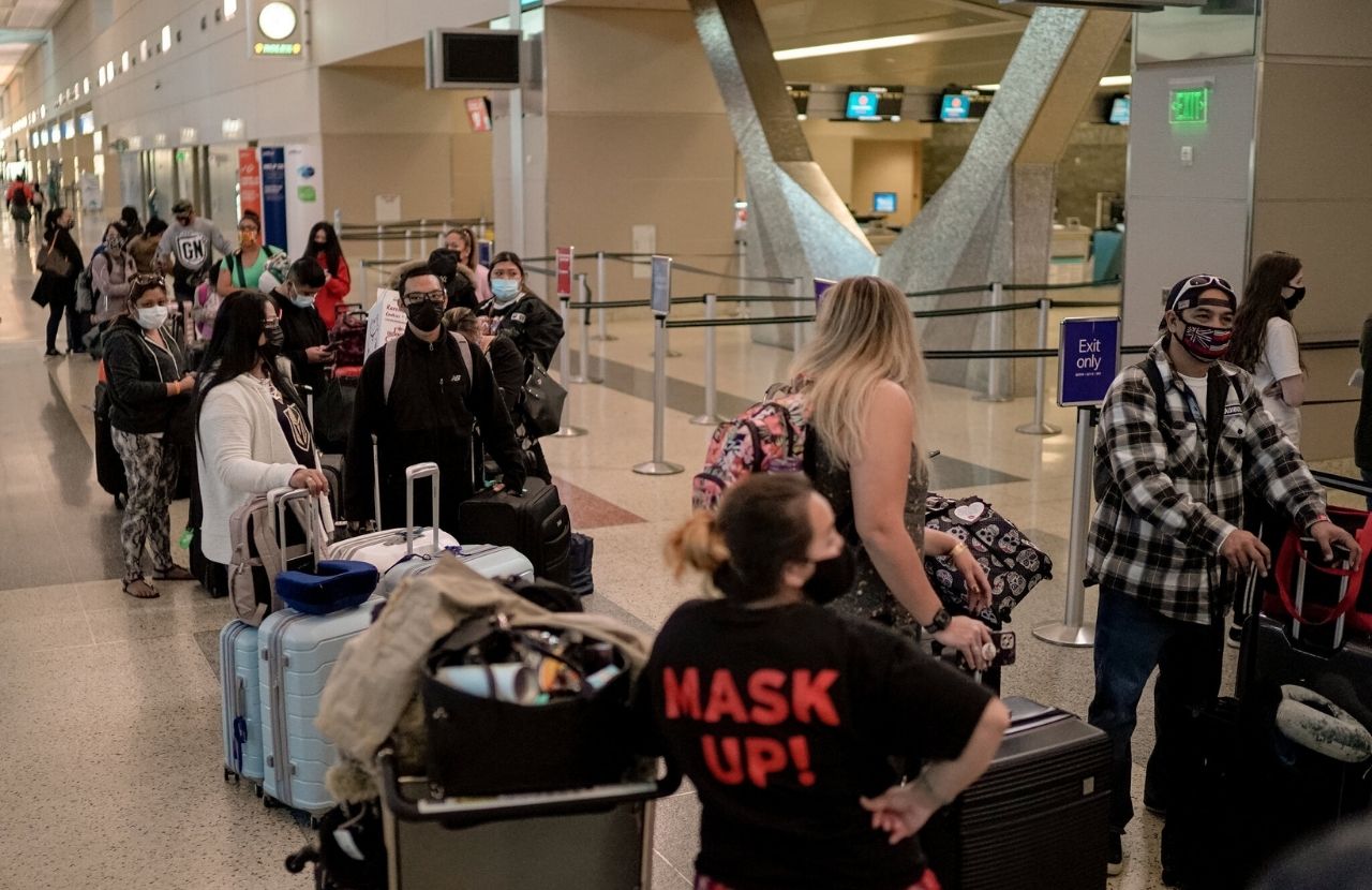 people standing in line to check their luggage at an airport
