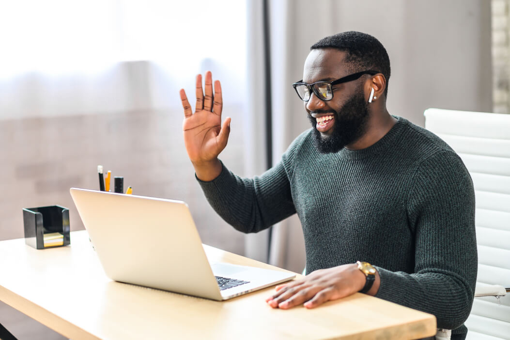 A web designer on laptop waving at computer