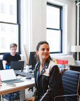 Image of a girl sitting at her desk, smiling and looking over her shoulder