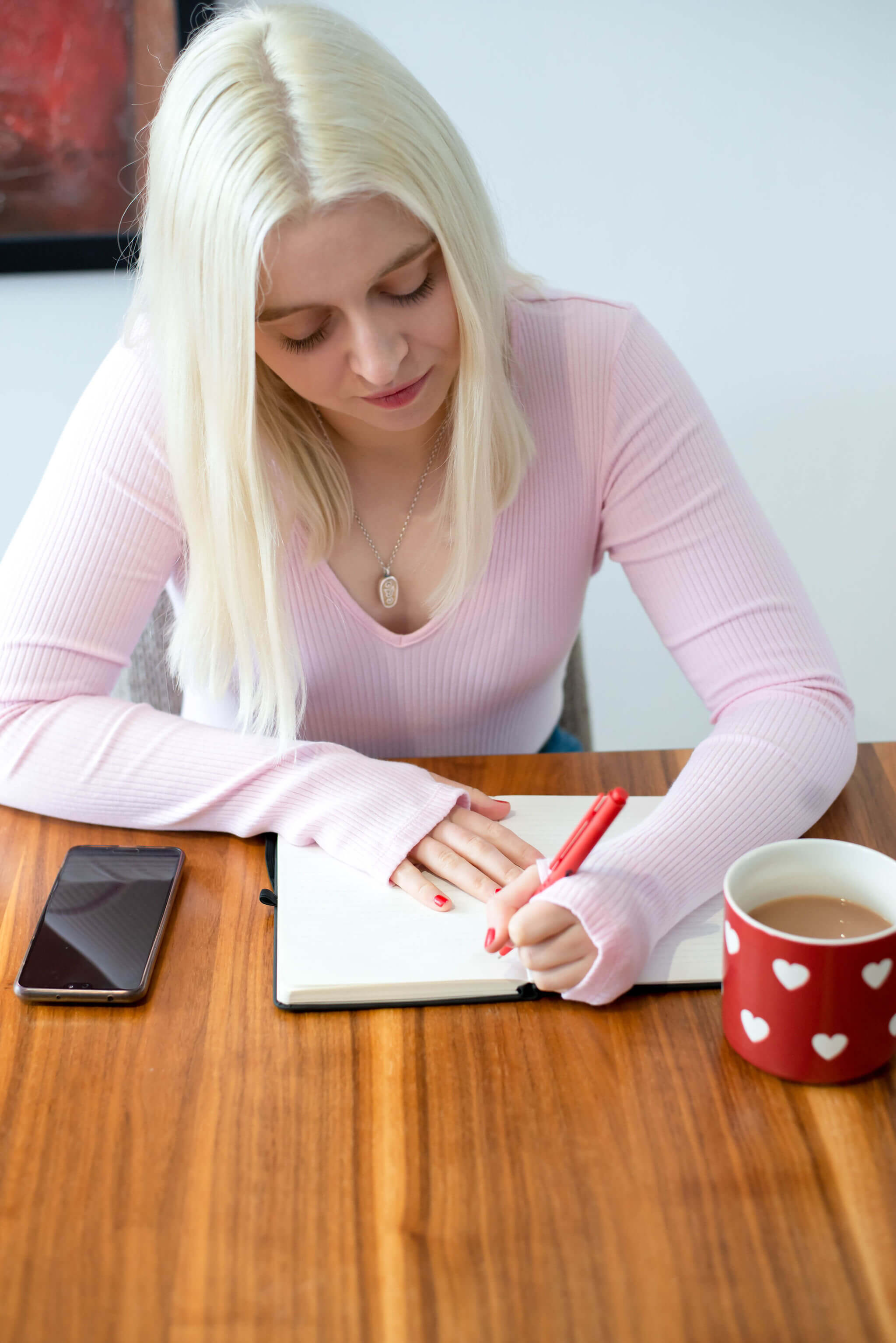 Emma sitting at a table leaning over a notepad as she writes down notes. 