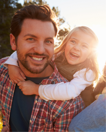 A happy father giving her daughter a piggyback ride. 
