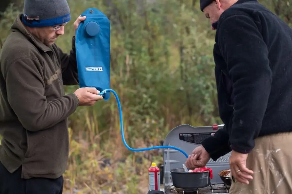 Man filters water into cooking stove outside
