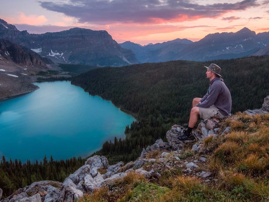 Hiker sitting on a rock above alpine lake