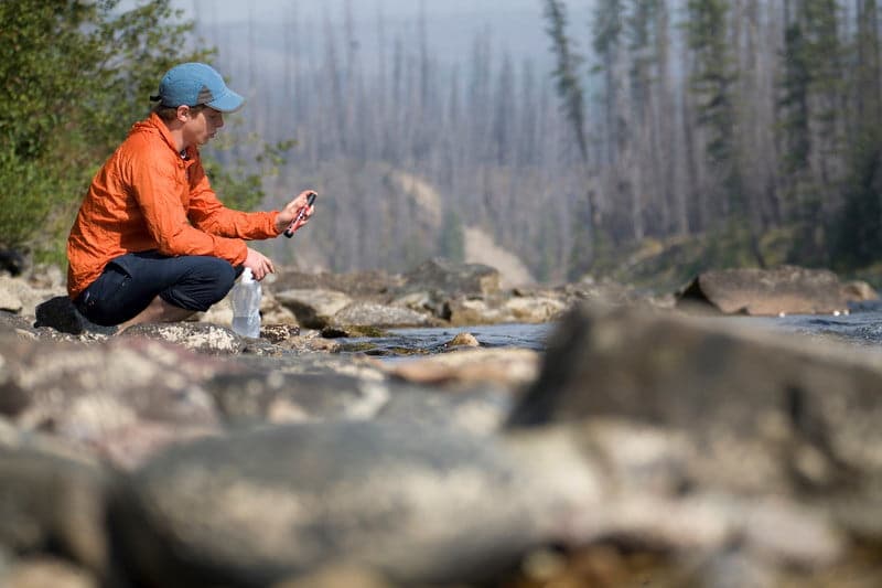 Young man checks water filter alongside river