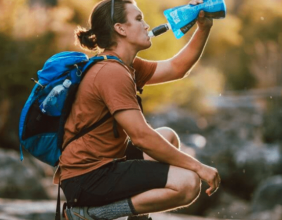 Hiker drinks directly from Sawyer filter on squeeze bag