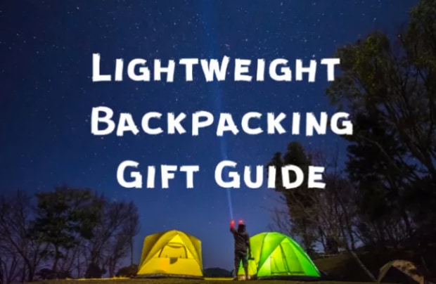 Hiker shines flashlight into dark sky next to lit up tents with words light weight backpacking gift guide