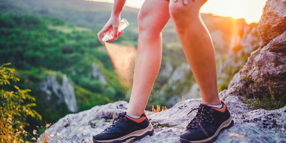 Person sprays bug repellent on shoes