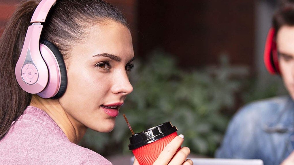 Woman wearing headphones drinking coffee