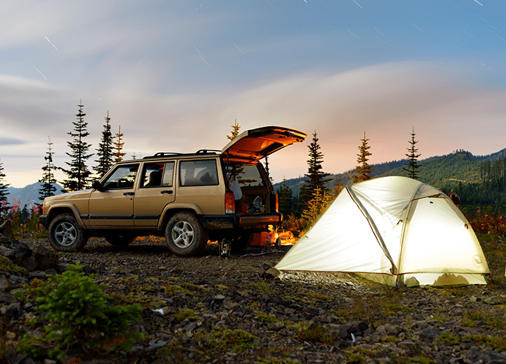 Tent in front of a car with back door open in the mountains