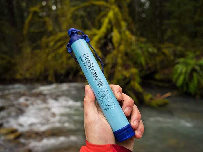 Hand holding Lifestraw in front of river