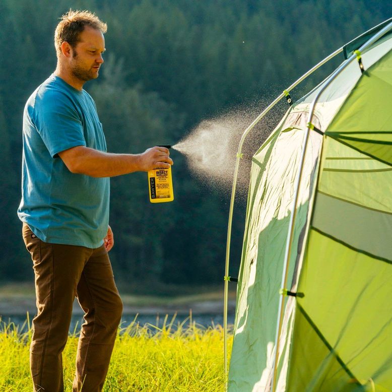 Man sprays permethrin on tent