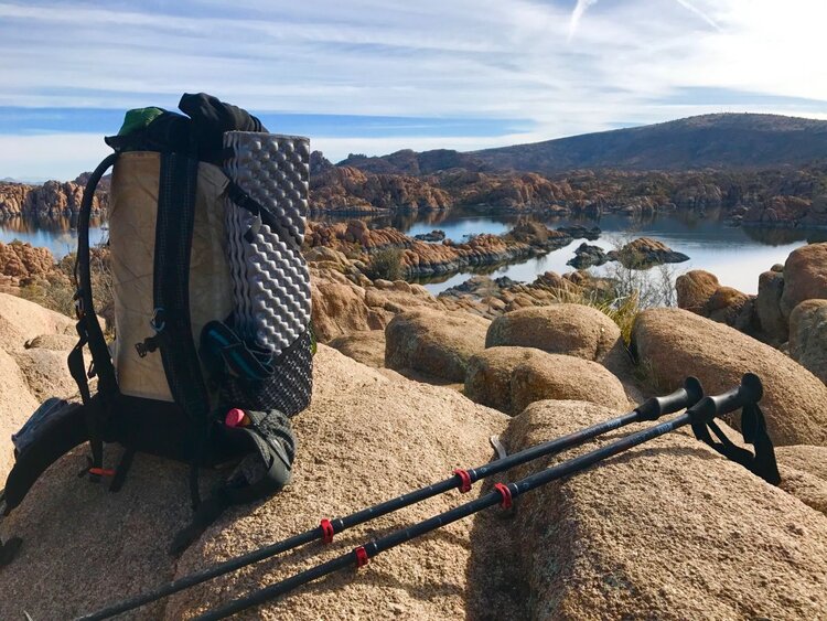 Backpack and trekking poles on rock above Watson Lake