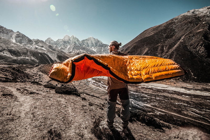 man with sleeping blanket or quilt in the mountains