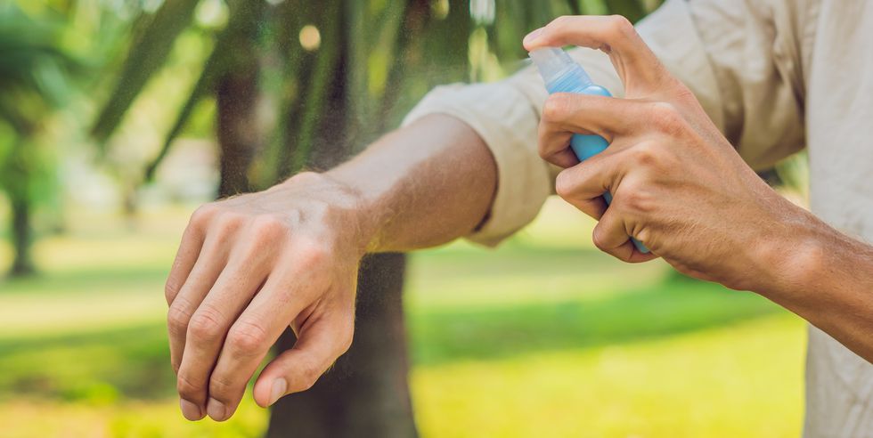 young man spraying mosquito insect repellent