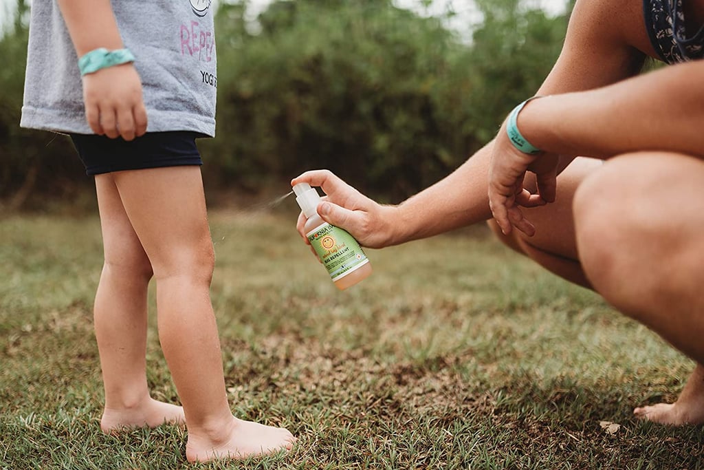 Mother applying bug spray on child