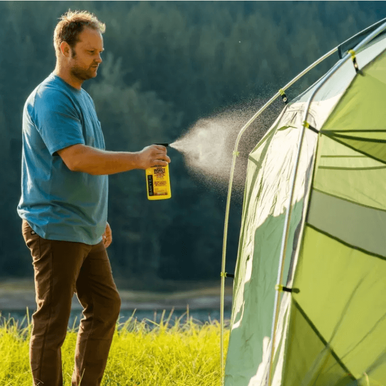 Man sprays permethrin on tent