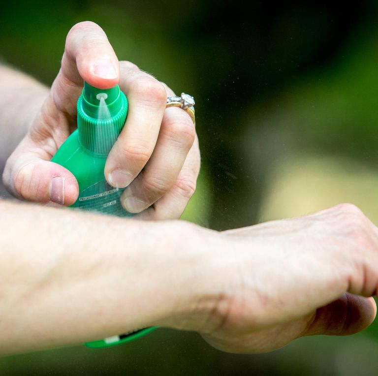 woman sprays herself with mosquito repellent