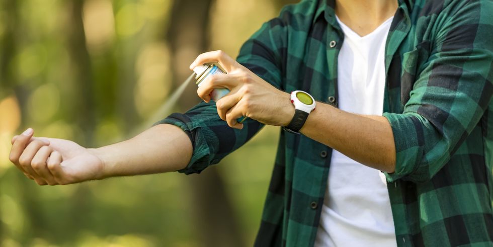 Person spraying mosquito repellent on arm