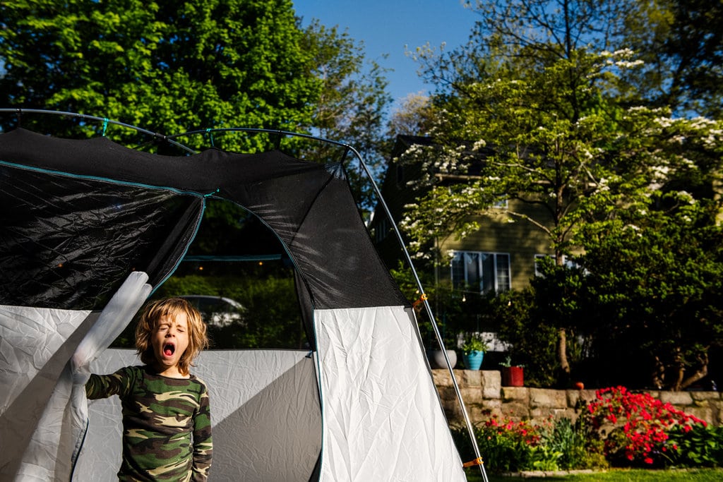 Child standing in a tent in the backyard