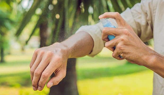 Person sprays arm with bug spray