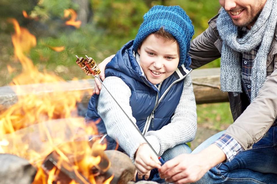 Father and son roasting marshmallow over fire