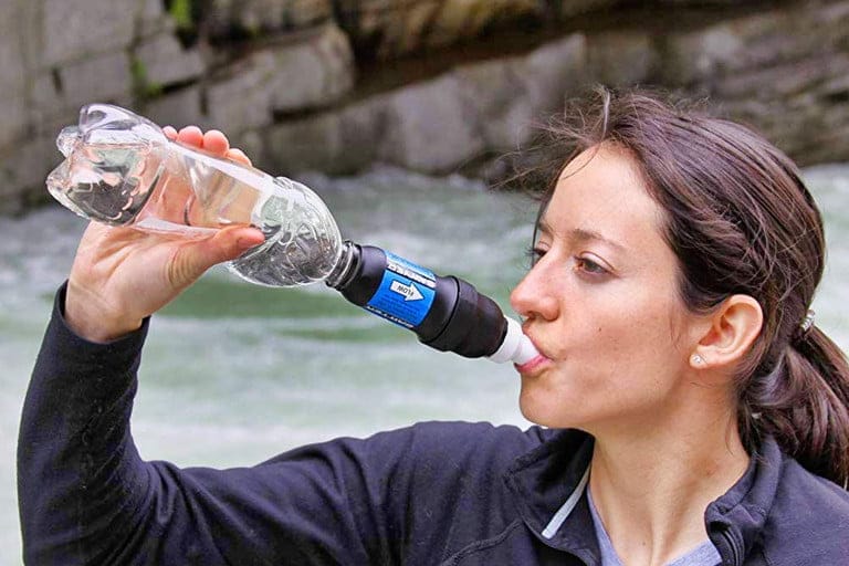 Woman drinks water directly from Sawyer filter attached to water bottle.